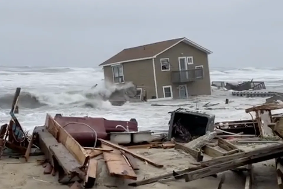 A house has been swept into the Atlantic Ocean by high tides, leaving ruins in onshore as the house appears half submerged by water,